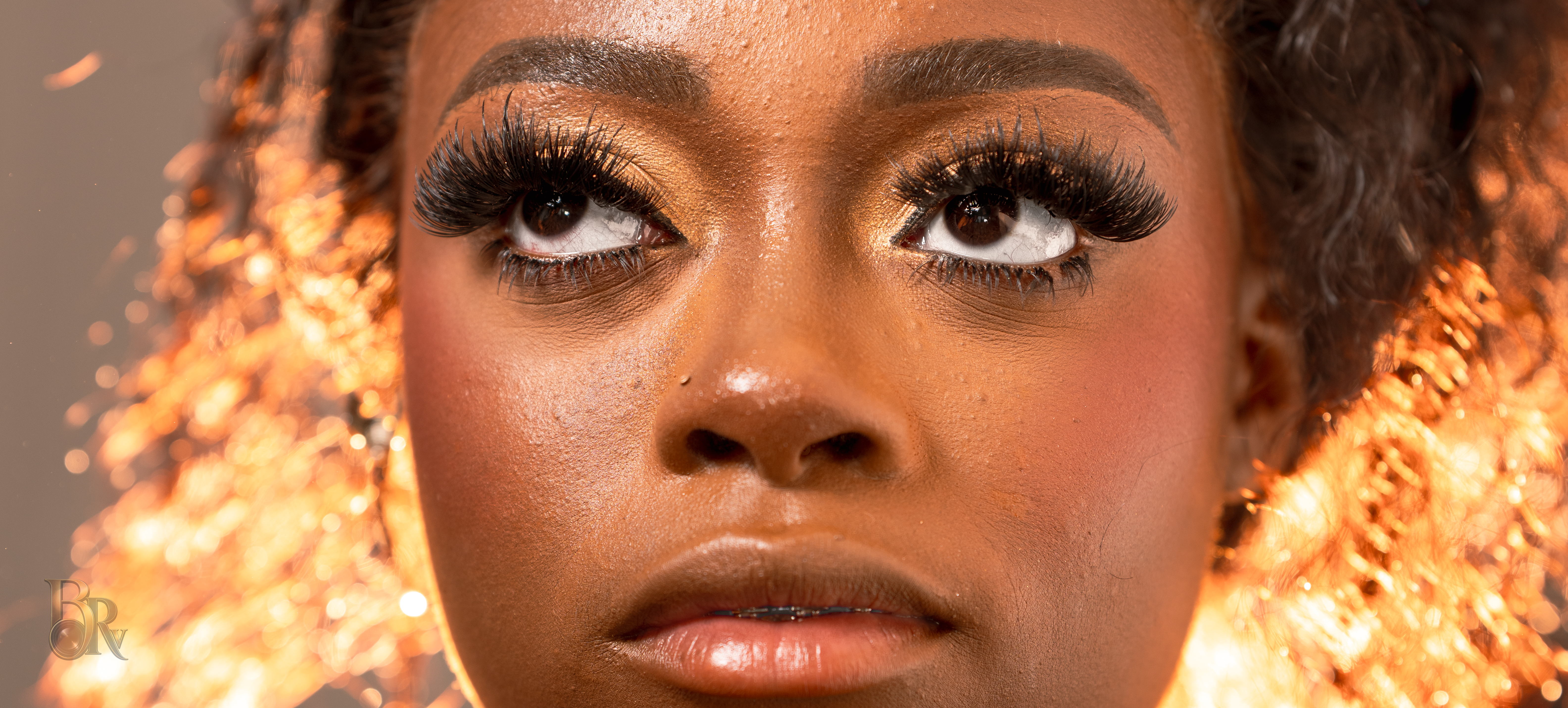 Beauty portrait close-up focused on expressive eyes, lashes, and warm glowing light by Big Rich Visuals