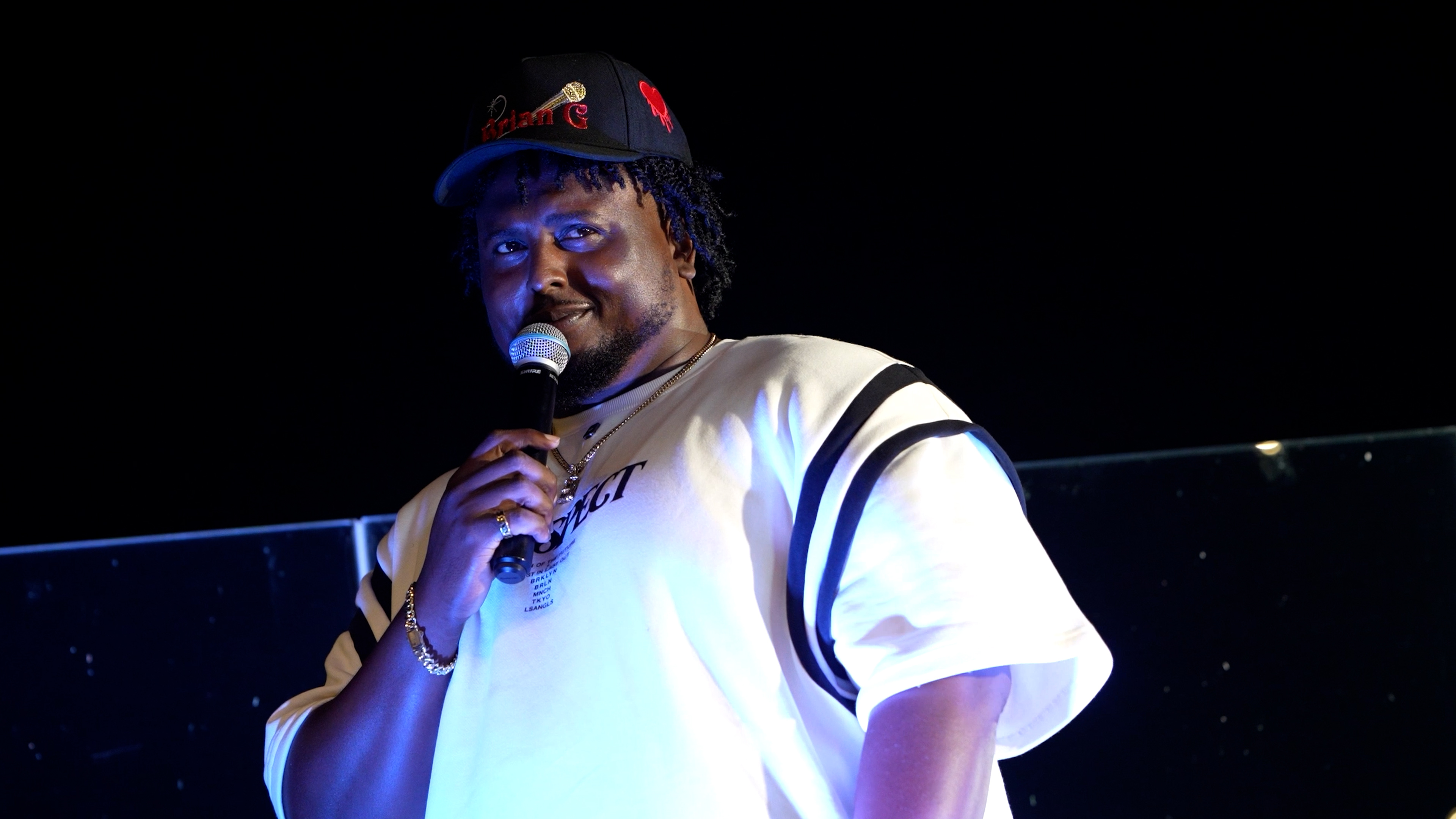 Live entertainment photography of a performer holding a microphone on a dark stage by Big Rich Visuals